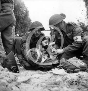 CAEN(14000) 15 juillet 1944 Deux infirmiers canadiens sont en train de soigner un bless, allong sur le sol.